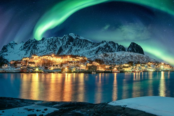 Aurora borealis arcing over a coastal village