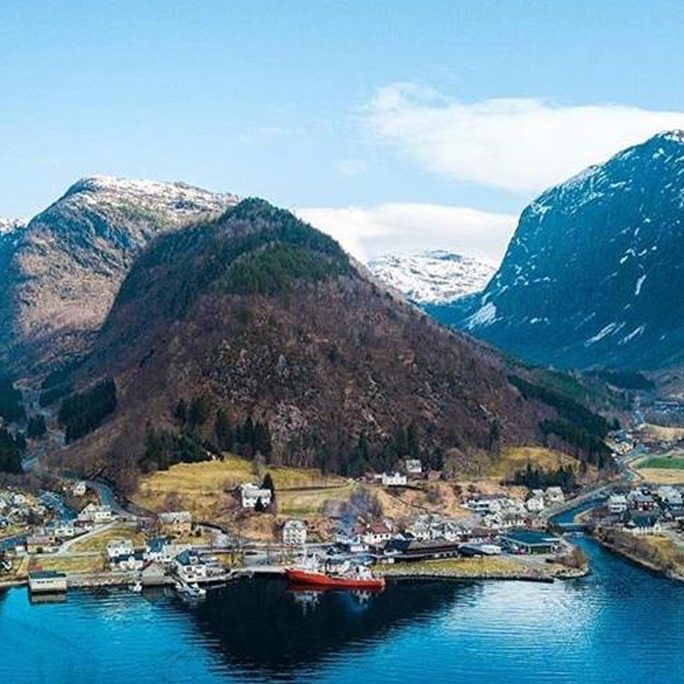 A harbour village on the water framed by forested mountains